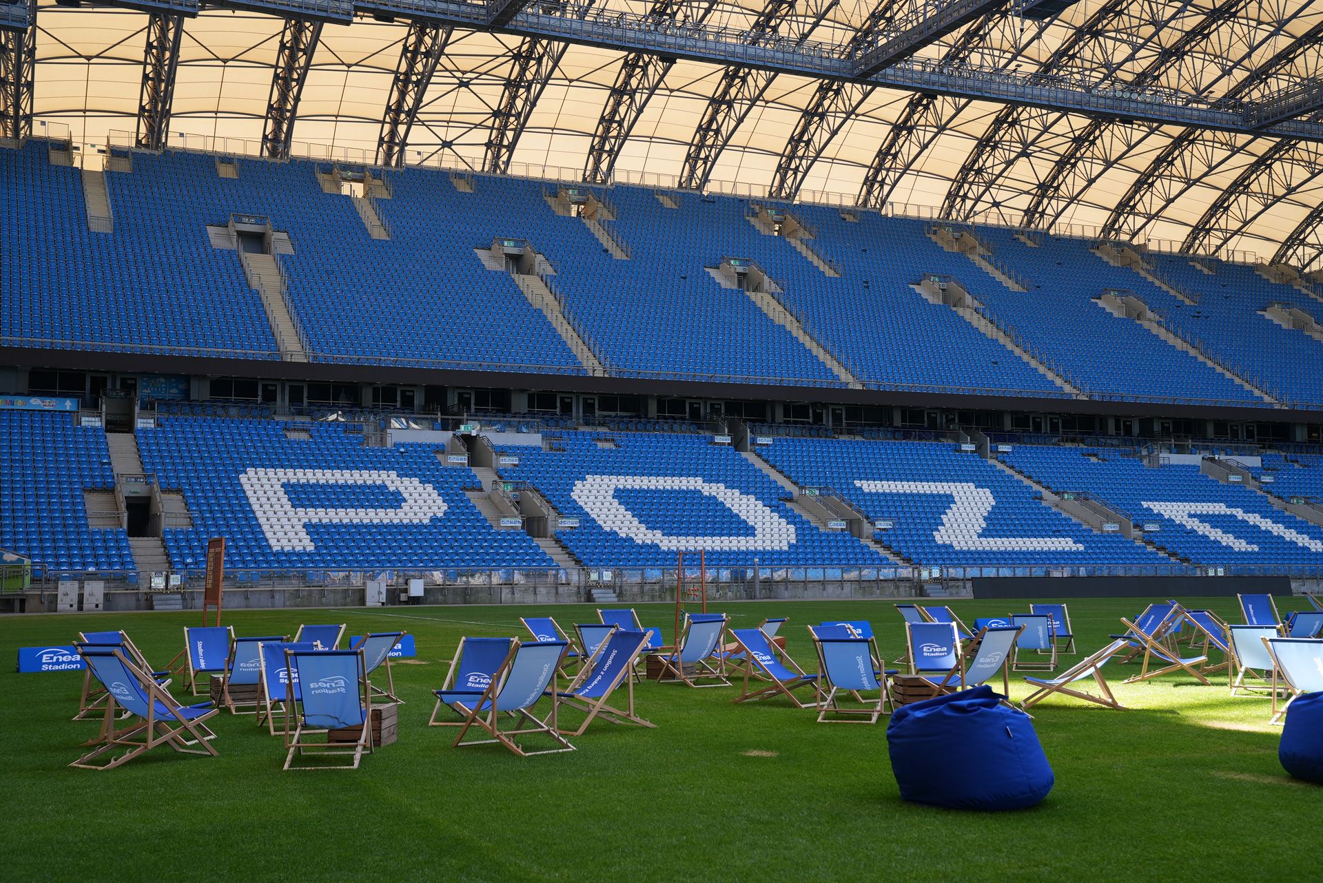 Leżaki na murawie na tle trybun Enea Stadionu